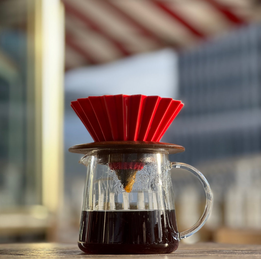 A cup of filter coffee subscription made from an origami dripper on a wooden table