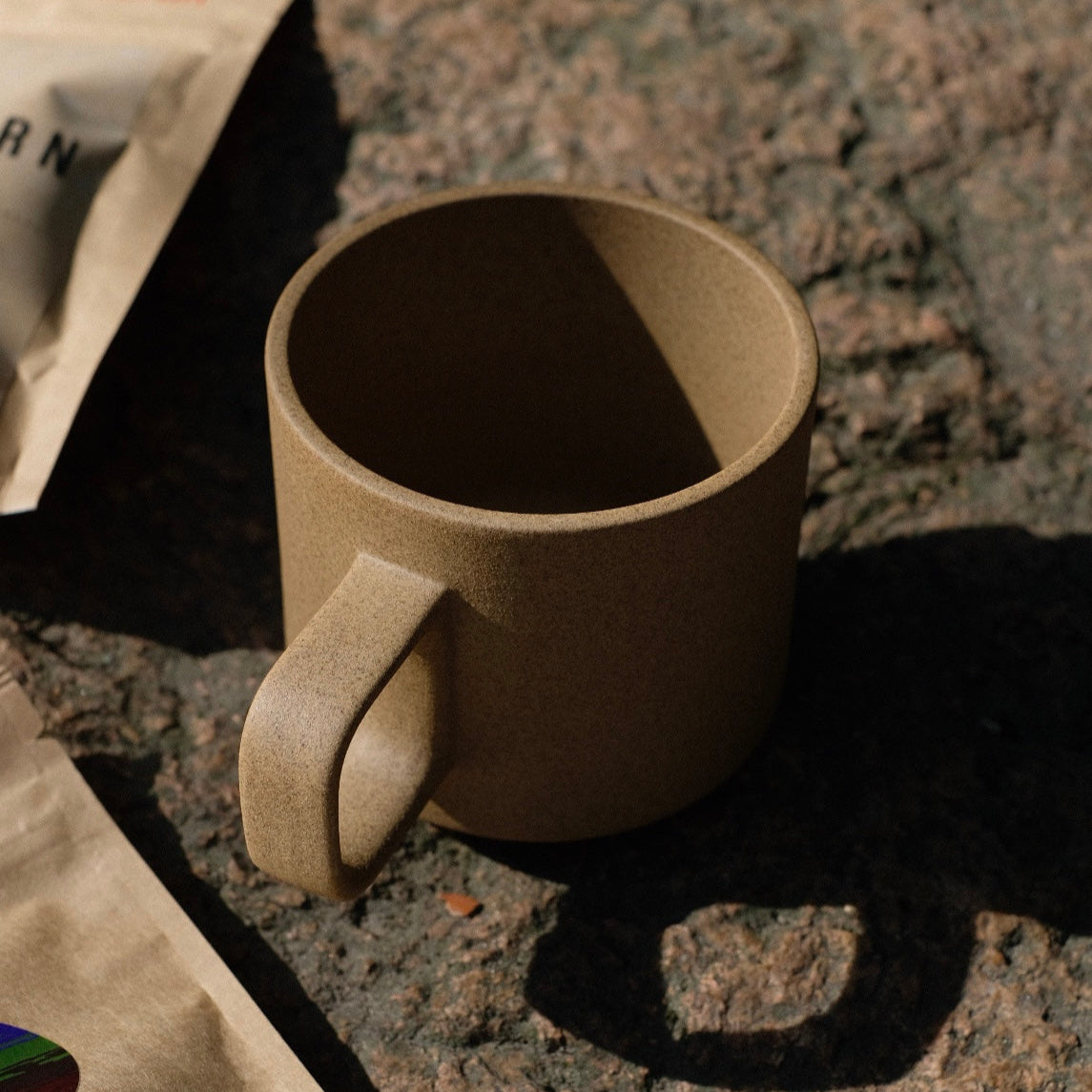 A beige Hasami mug, against a background of natural stone. 