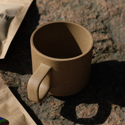 A beige Hasami mug, against a background of natural stone. 