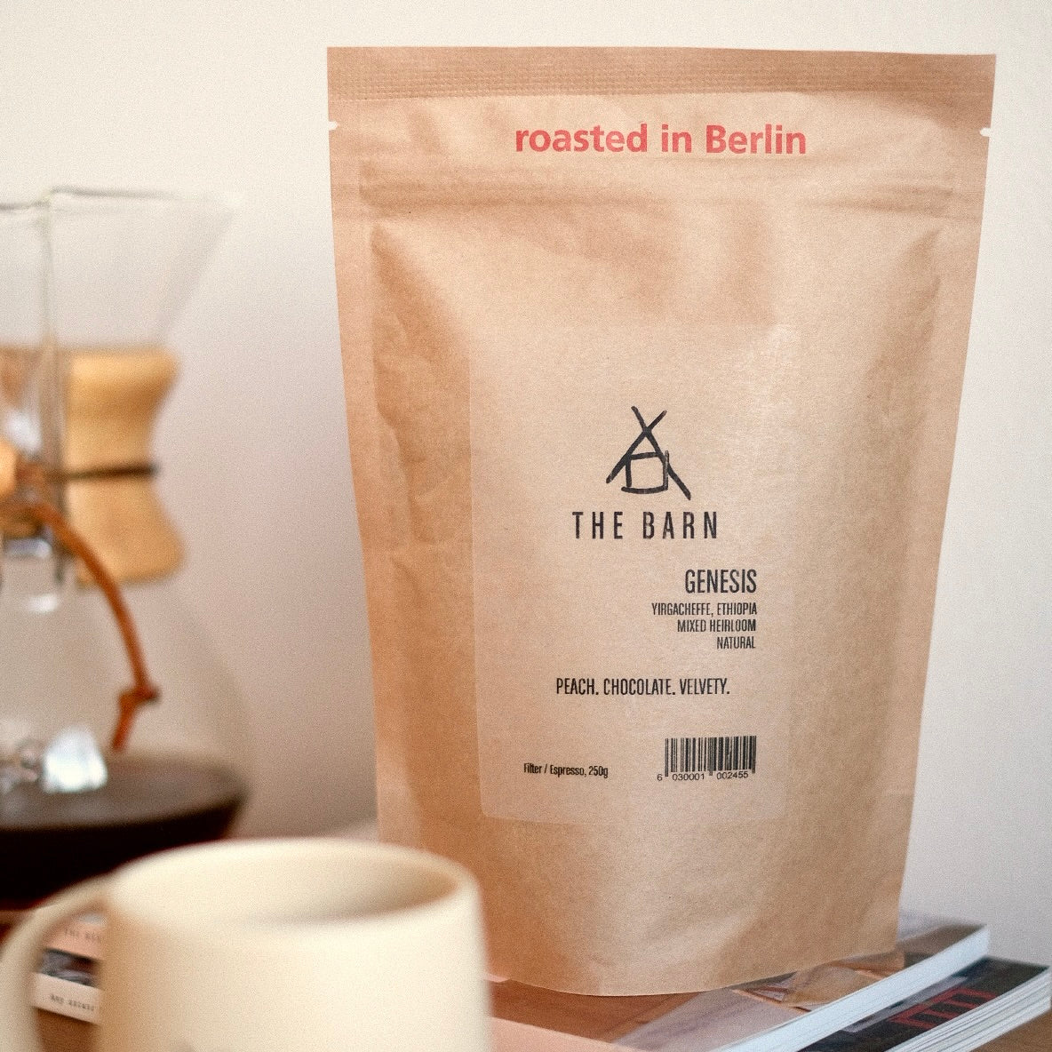 A 250g Brown Coffee Bag of Genesis Coffee from Ethiopia, Yirgacheffe on a stack of books on-top of a wooden table.