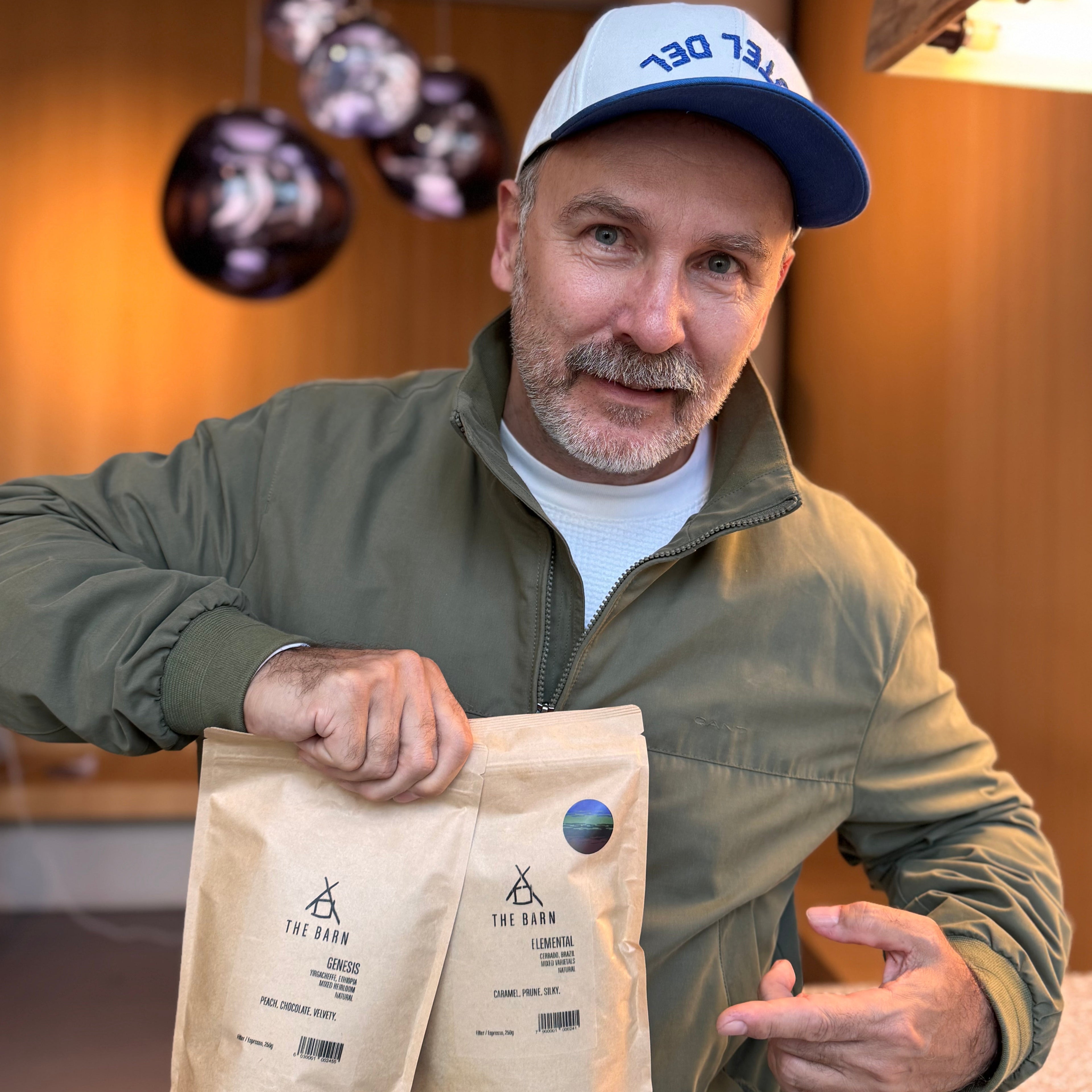 Ralf Ruller holding two coffee bags sized 250g from the Barn "Genesis and Elemental Coffee"