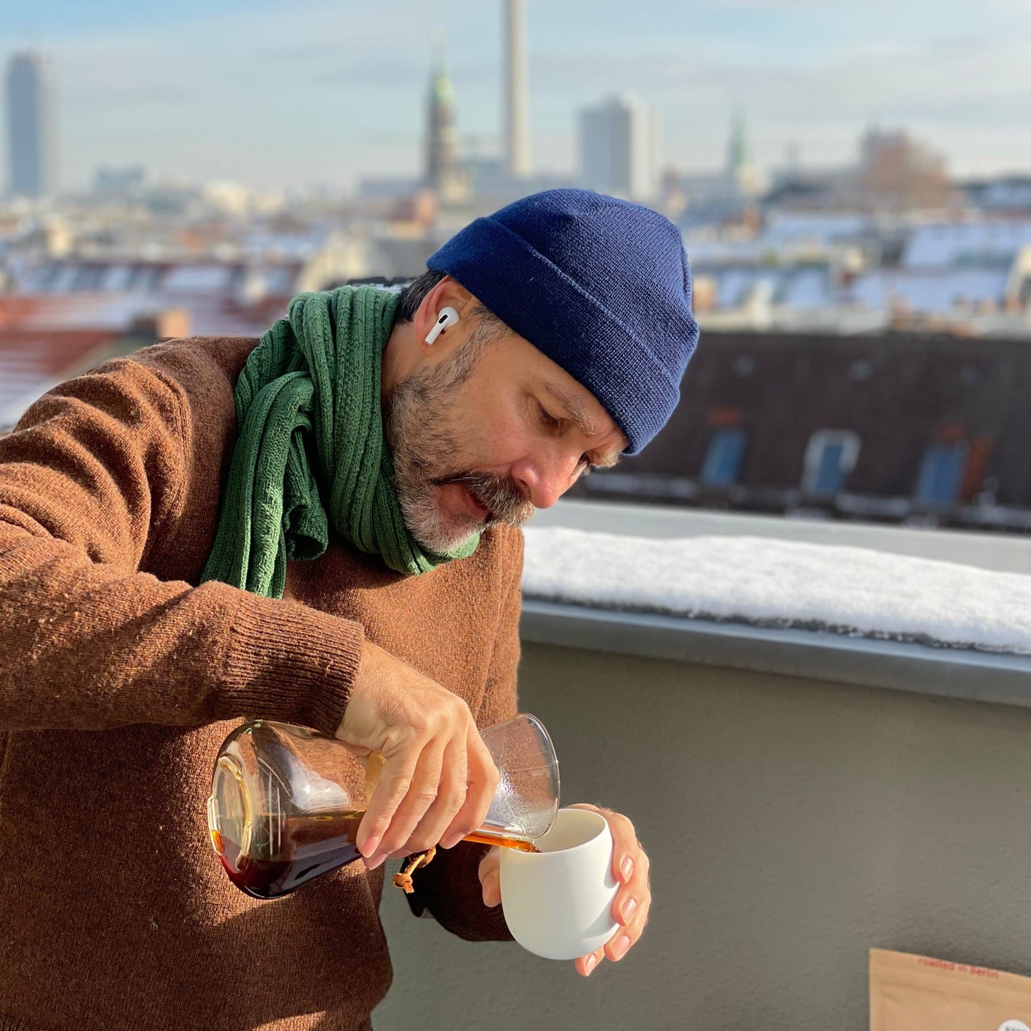 Ralf Rüller, the founder of THE BARN Berlin, is pouring freshly roasted coffee from a chemex into a ceramic mug