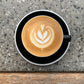 Overhead view of a ceramic espresso cup filled with latte art design made of steamed milk on top